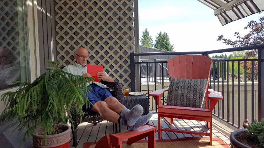 person-in-chair-reads-on-deck-in-shade-of-retractable-awning Person in chair reads on deck in shade of retractable awning